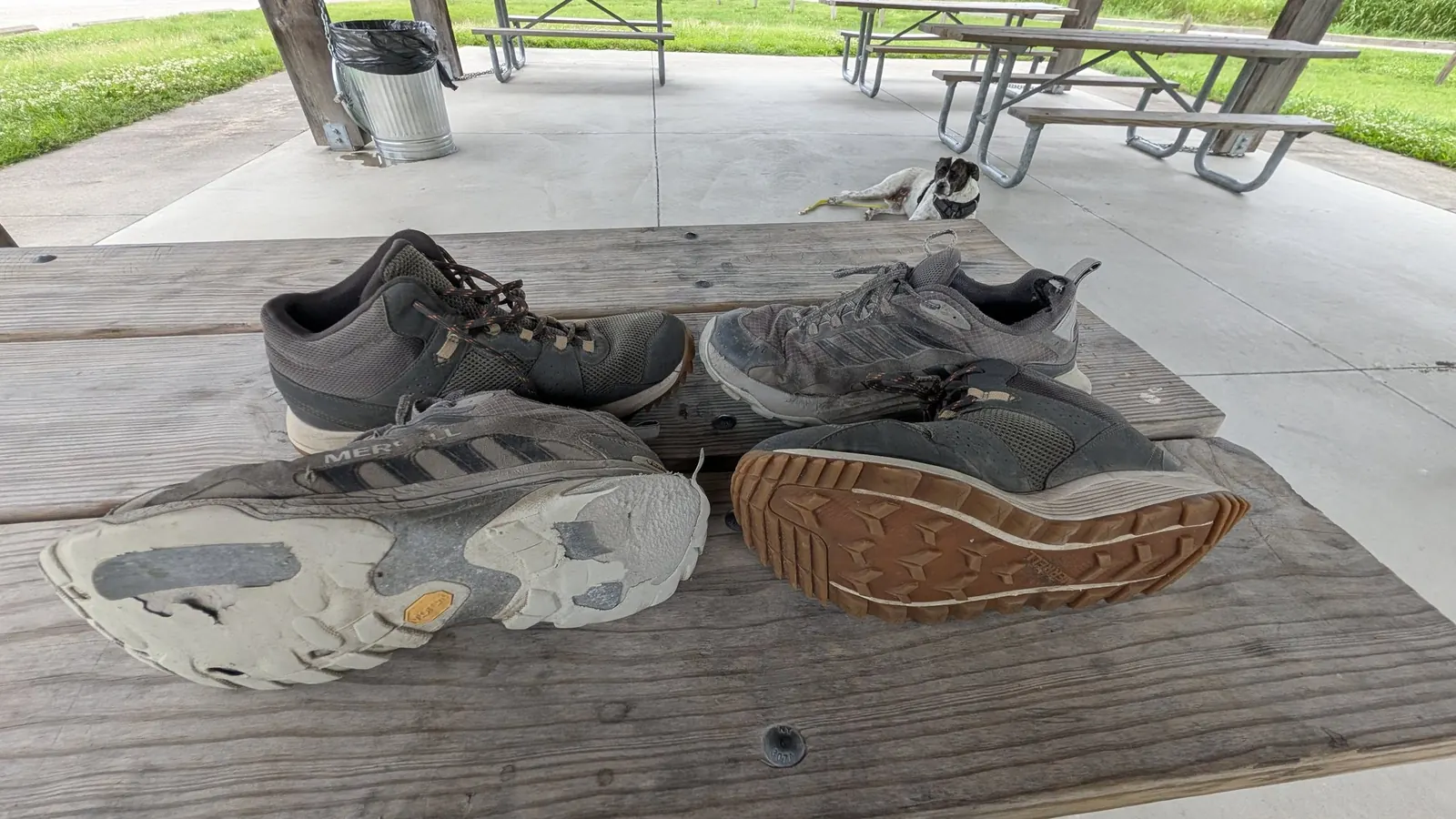 Several pairs of worn trail shoes on a picnic table